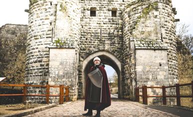 Une personne déguisée en chevalier devant un château fort